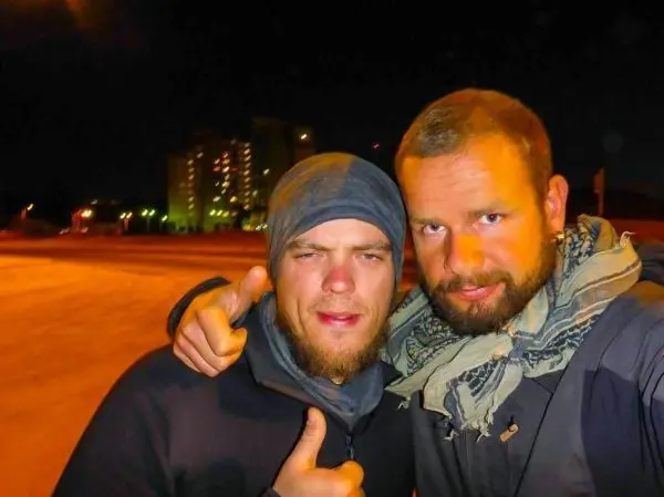 Zwei Männer posieren in der Nacht, einer zeigt Daumen hoch
