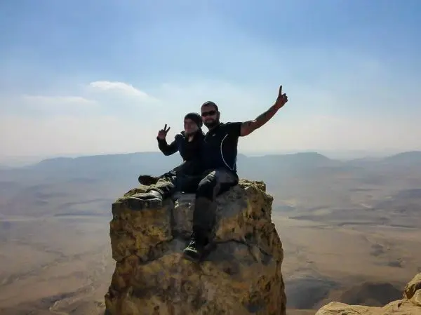 Zwei Personen sitzen auf einem großen Felsen mit Blick auf die Landschaft