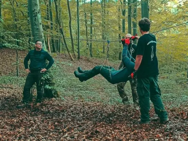 Drei Personen bedienen eine selbstgebaute Seilquerung im Wald