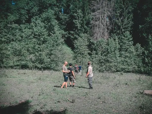 Gruppe steht auf einer Wiese und diskutiert im Wald