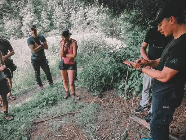 Gruppe von Personen im Wald, eine Person hält ein Seil