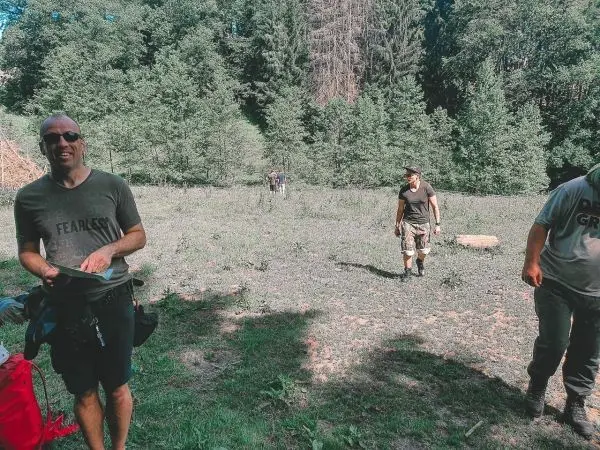 Gruppe von Personen wandert durch eine bewaldete Fläche mit hohem Gras