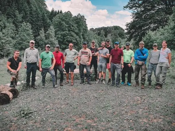 Gruppierung von Personen im Freien, umgeben von Bäumen und Grasfläche