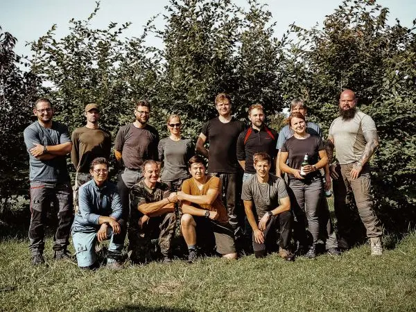 Gruppierung von Personen im Freien, umgeben von Büschen und Gras