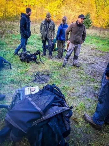 Gruppe steht um Rucksäcke auf dem Boden in einer Wiese