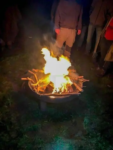 Kleine Flamme brennt in einem Feuerkorb mit Holzscheiten