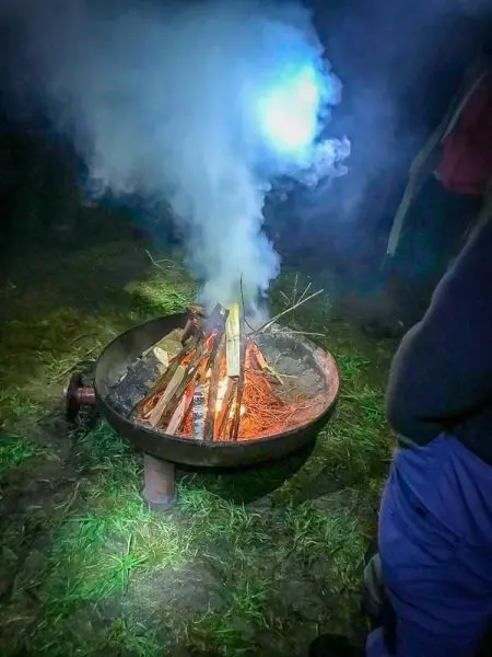 Kleine Flamme mit Rauch aus Holzscheiten in einer Feuerschale
