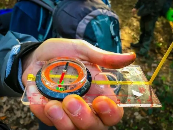 Kompass in Hand zeigt Richtung mit rotem Pfeil und gelber Skala