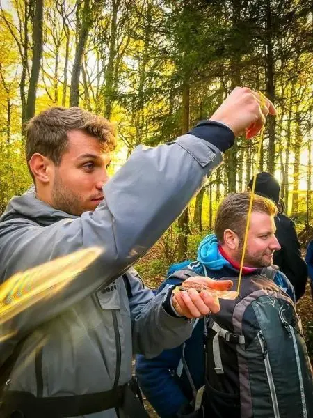 Mann hält eine Schnur in der Hand und misst die Länge im Wald