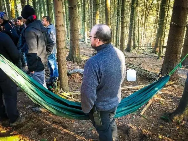 Mann steht neben einer hängenden Hängematte im Wald