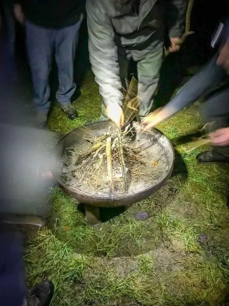 Personen fügen Holz zu einem Feuer in einer Feuerschale hinzu
