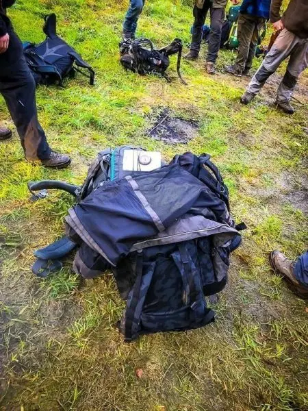 Rucksack liegt auf dem Boden, umgeben von weiteren Rucksäcken und Personen