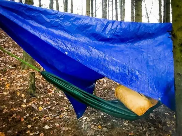 Tarp-Notunterkunft hängt über einer Hängematte zwischen Bäumen