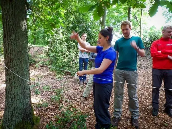 Frau erklärt die Technik einer Seilquerung an einem Baum