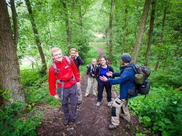 Gruppe von Wanderern auf einem Waldweg, einige lachen und unterhalten sich