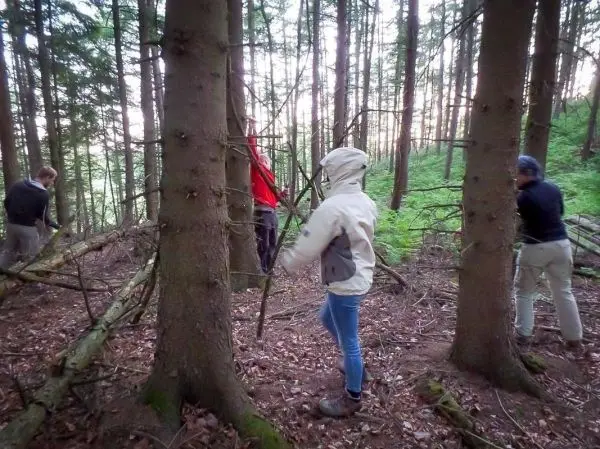 Gruppierung arbeitet an einer selbstgebauten Seilbrücke zwischen zwei Bäumen