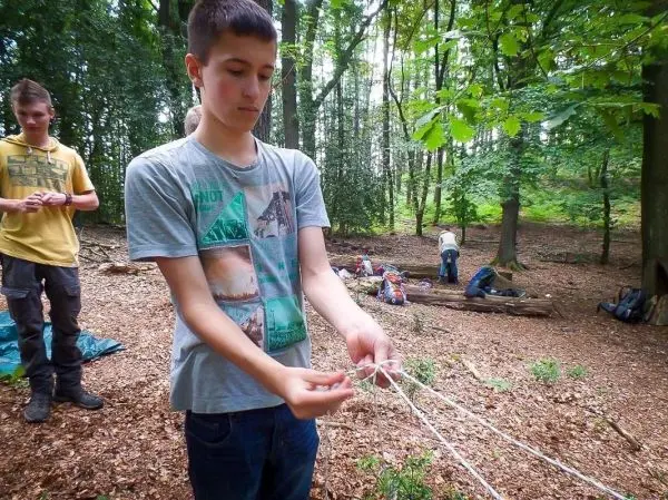 Junge bindet Seile zu einem Knoten im Wald