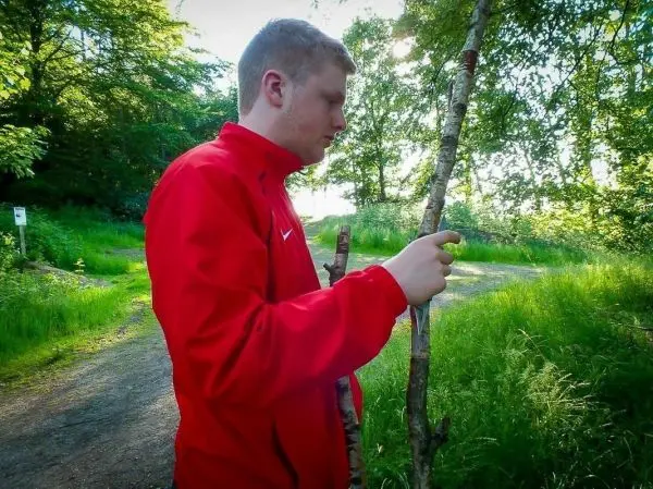 Junger Mann bearbeitet einen Stock mit einem Messer im Freien