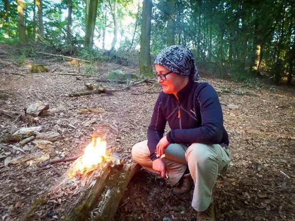 Kleine Flamme brennt auf einem Holzstamm im Wald