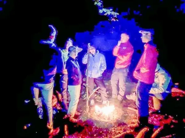 Kleines Bodenfeuer in der Mitte einer Gruppe von Personen im Dunkeln