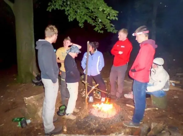 Kleines Bodenfeuer in der Mitte einer Gruppe von sechs Personen