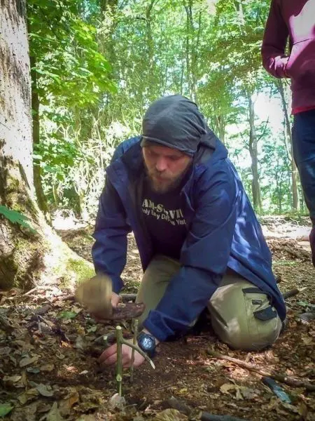 Mann baut eine Schlagfalle (Figure-Four-Falle) im Wald