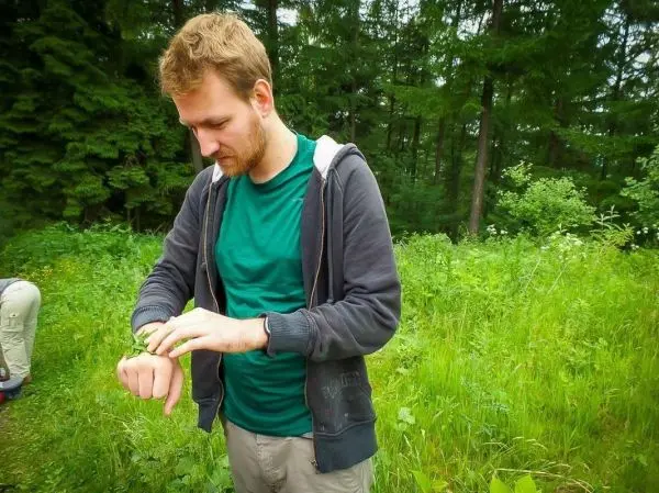 Mann überprüft seine Uhr in einer grünen Wiese umgeben von Bäumen