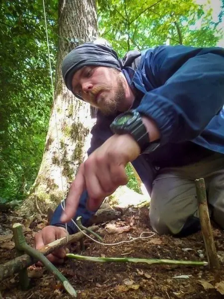 Person baut eine Falle aus Ästen im Wald