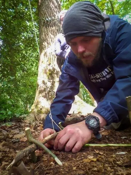 Person baut eine Konstruktion aus Ästen im Wald
