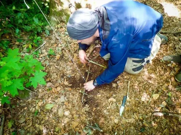 Person baut eine Konstruktion aus Ästen im Wald