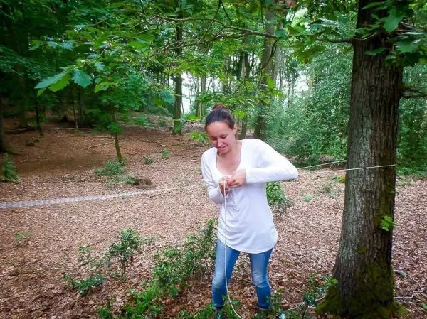 Person bindet ein Seil an einen Baum im Wald