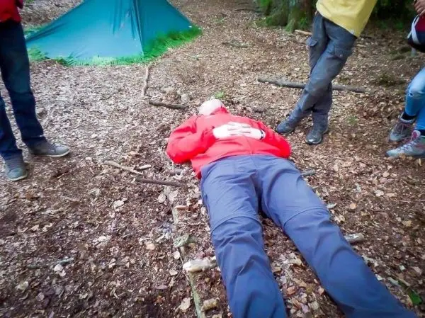 Person liegt auf dem Boden, umgeben von anderen Personen und einem Tarp