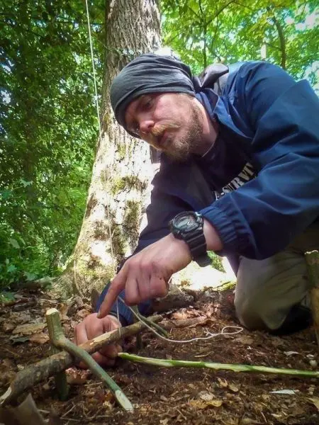 Person zeigt auf eine selbstgebaute Vorrichtung im Wald