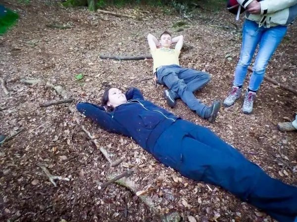 Personen liegen auf dem Boden im Wald und entspannen