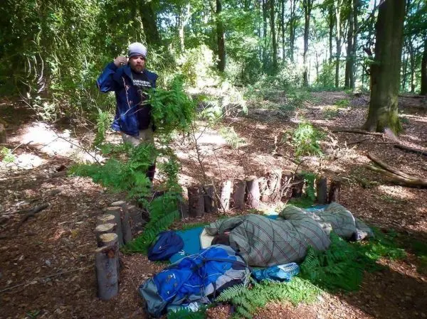 Selbstgebaute Notunterkunft aus Ästen und Holzstämmen im Wald