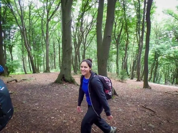 Wandernde Person mit Rucksack im Wald zwischen Bäumen
