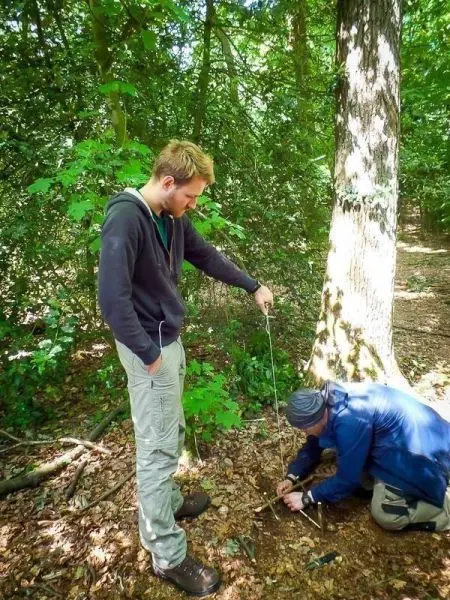 Zwei Personen arbeiten im Wald an einer selbstgebauten Schlagfalle