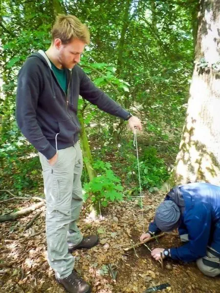 Zwei Personen arbeiten im Wald an einer selbstgebauten Schlagfalle
