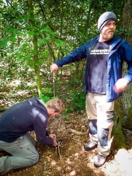 Zwei Personen bauen eine Schlagfalle im Wald auf