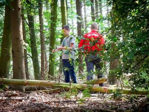 Zwei Personen stehen im Wald und betrachten ein Gerät