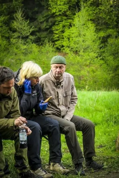 Drei Personen sitzen auf einer Bank und unterhalten sich im Freien