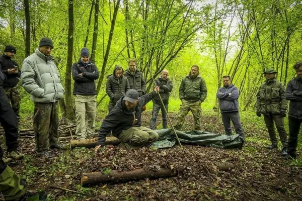 Ein Teilnehmer demonstriert den Aufbau einer Tarp-Notunterkunft im Wald