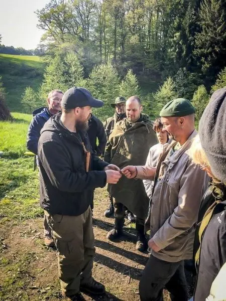 Eine Person übergibt ein Werkzeug an eine andere Person in einer Gruppe im Freien