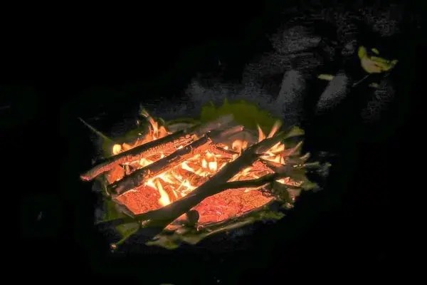 Feuer brennt zwischen Holzstücken im Dunkeln