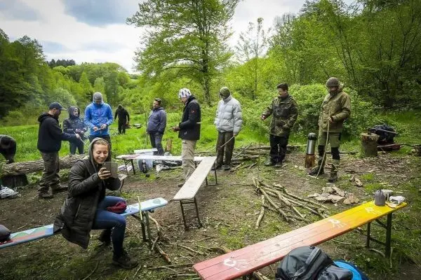 Gruppe arbeitet an einem Lagerplatz mit Holz und Ausrüstung im Freien