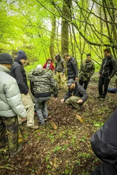 Gruppe betrachtet Bodenstelle im Wald mit Laub und Holzstücken