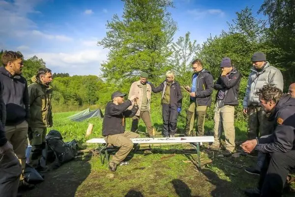 Gruppe diskutiert an einem Tisch über Überlebenstechniken im Freien