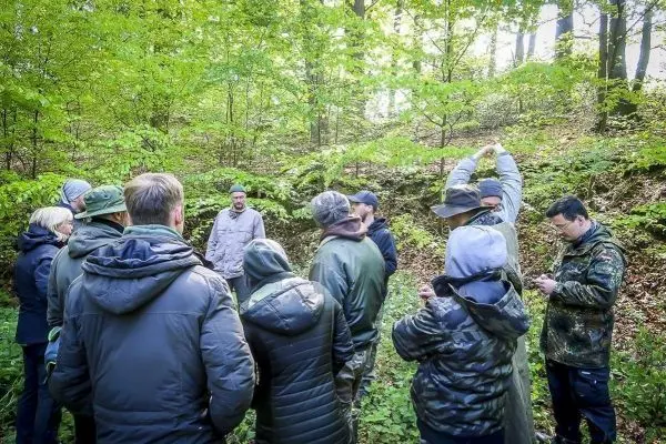 Gruppe diskutiert im Wald, umgeben von Bäumen und grüner Vegetation