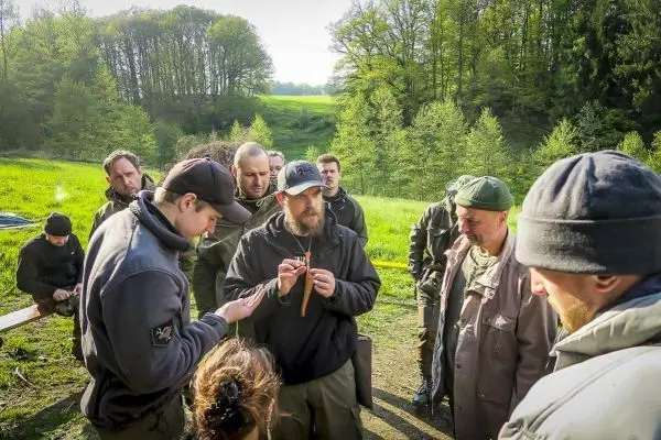Gruppe diskutiert Techniken zur Holzverarbeitung im Freien
