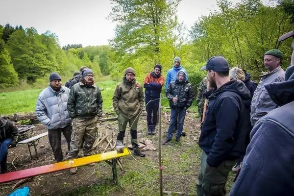 Gruppe diskutiert um selbstgebaute Konstruktion im Freien